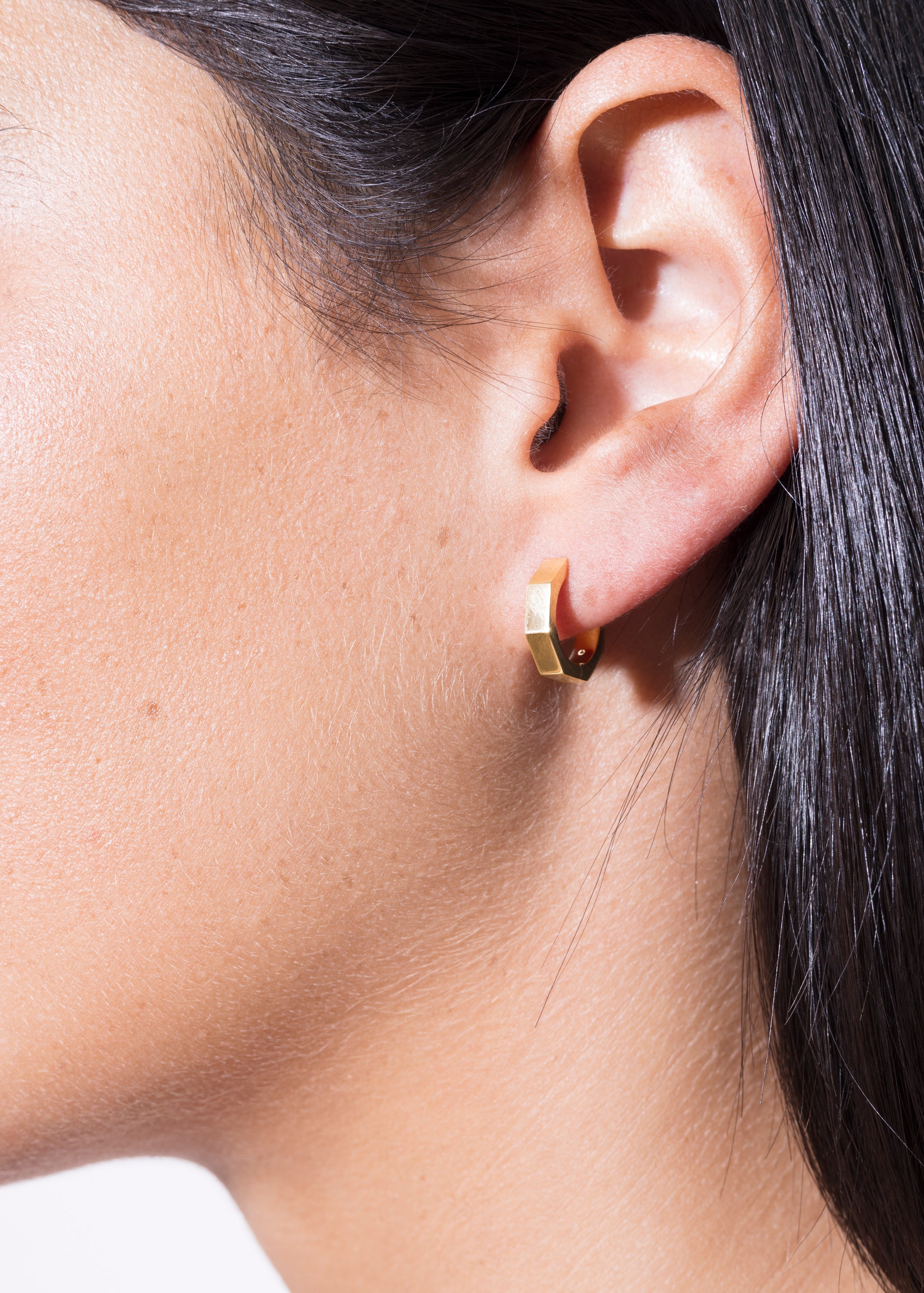 model wearing heptagon huggies 18k
