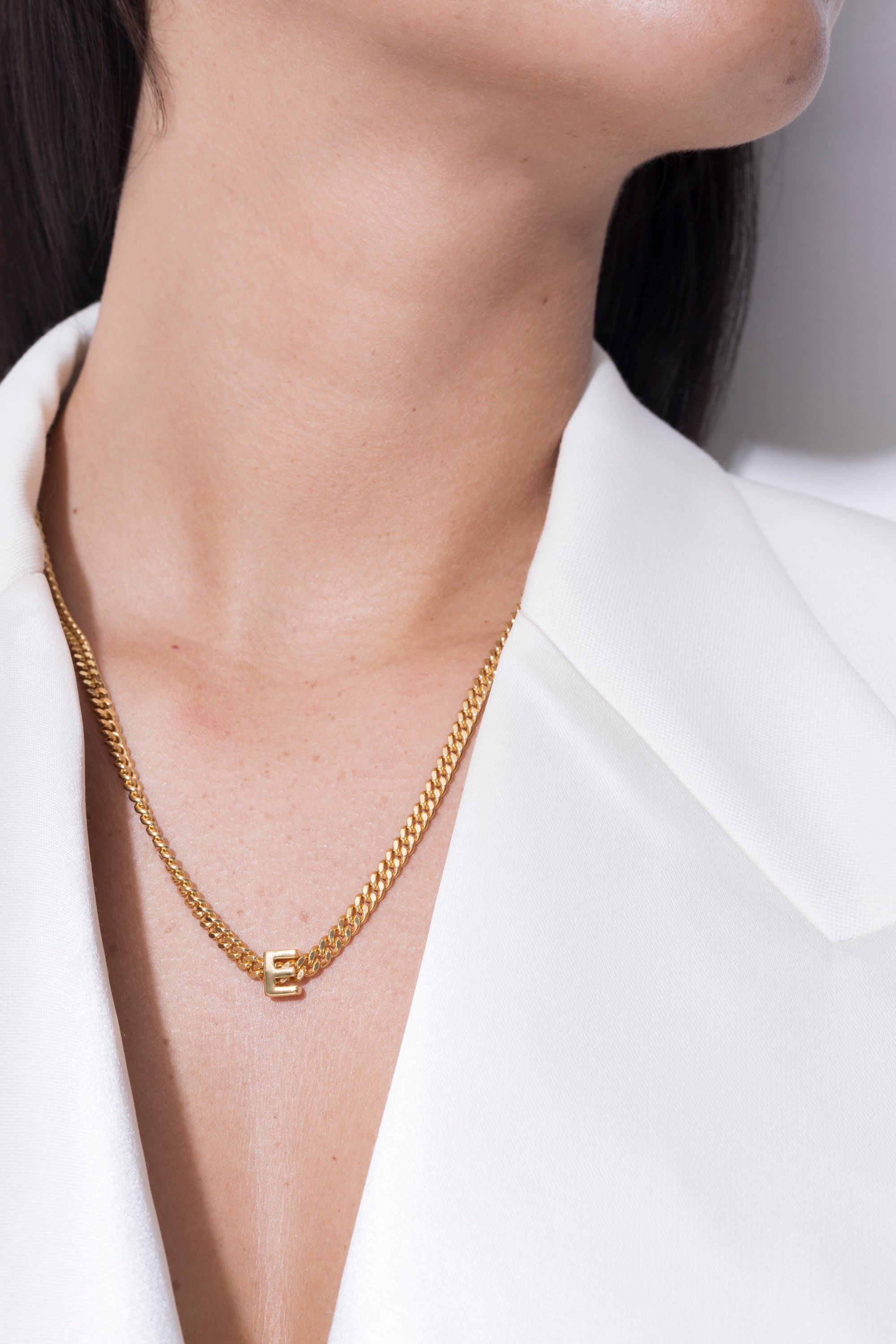 model wearing alphabet necklace with pendant E in gold
