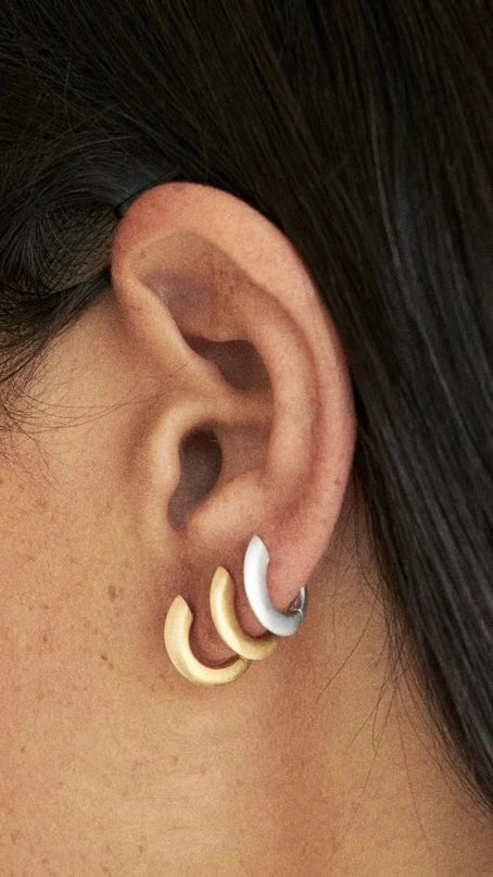Brincos huggie in different styles adorning an ear, showcasing the trend of ear stack.