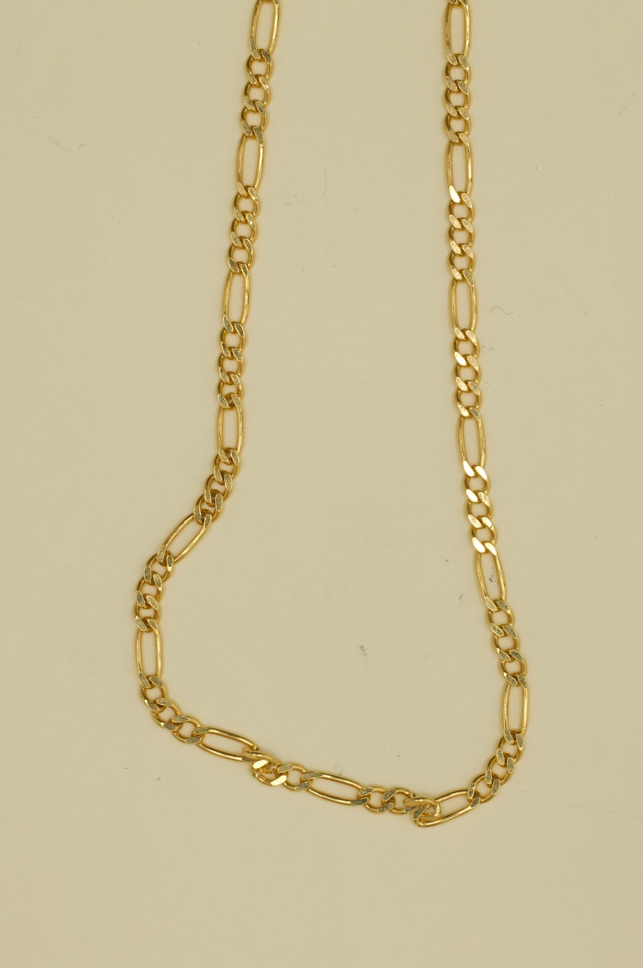 Gold chain necklace on a beige background