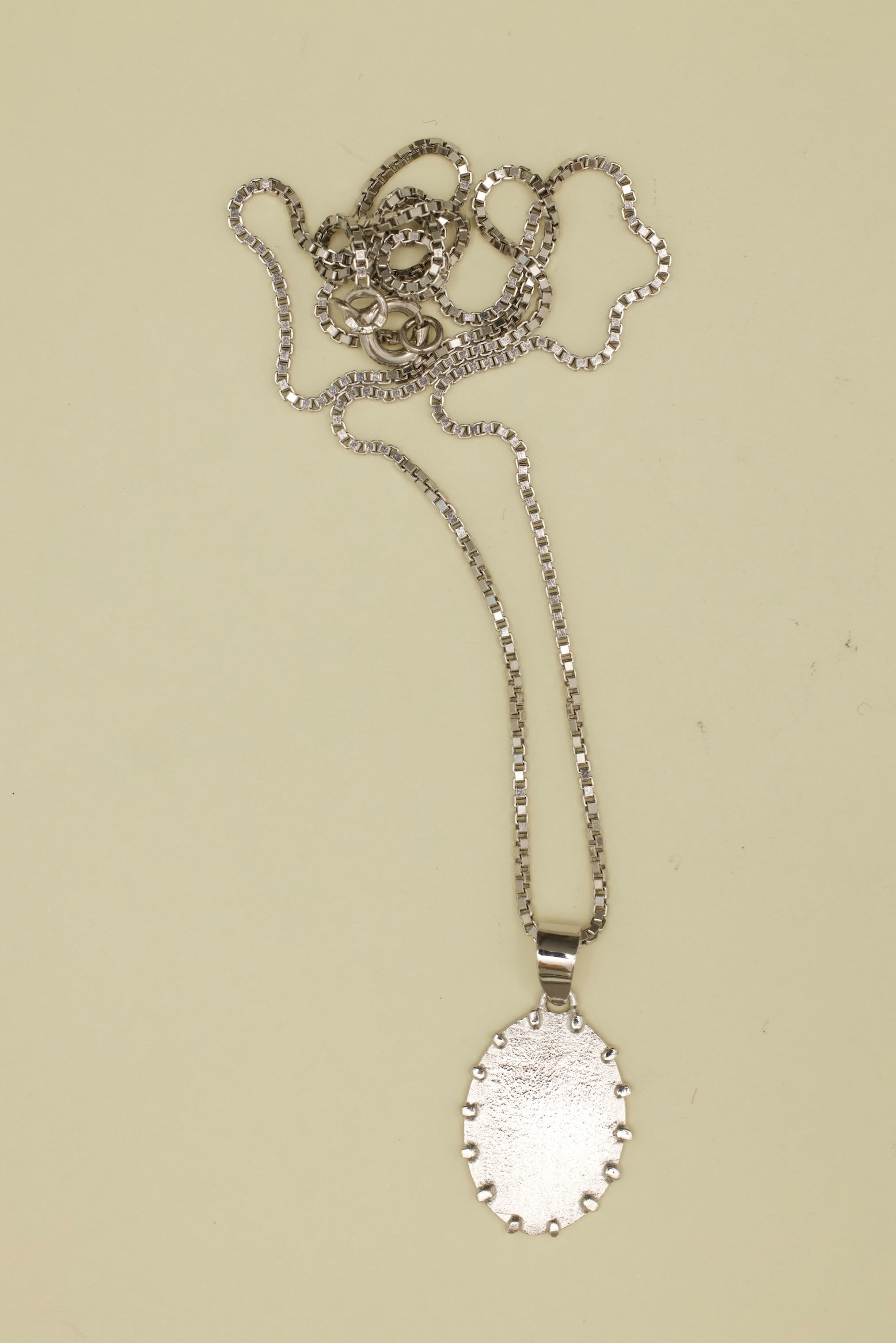 Silver necklace with a pendant on a beige background