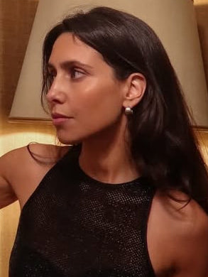 Woman standing in a room with a lamp and jewelry display