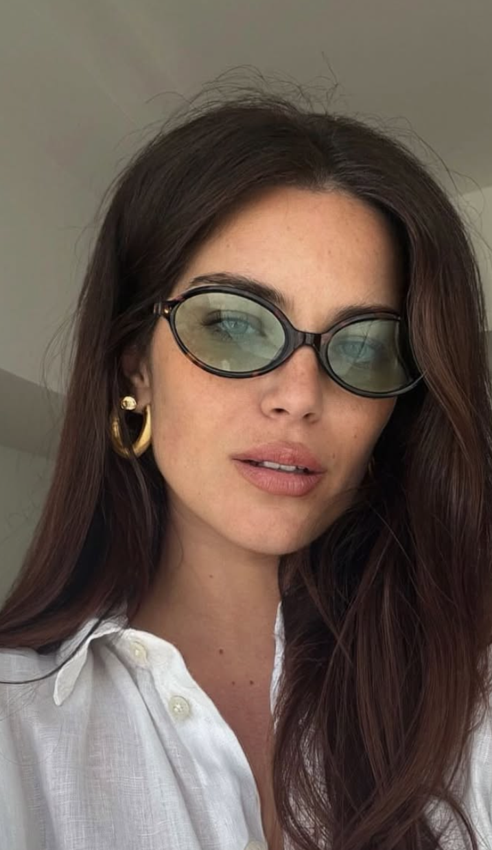 Woman wearing sunglasses and a white shirt indoors