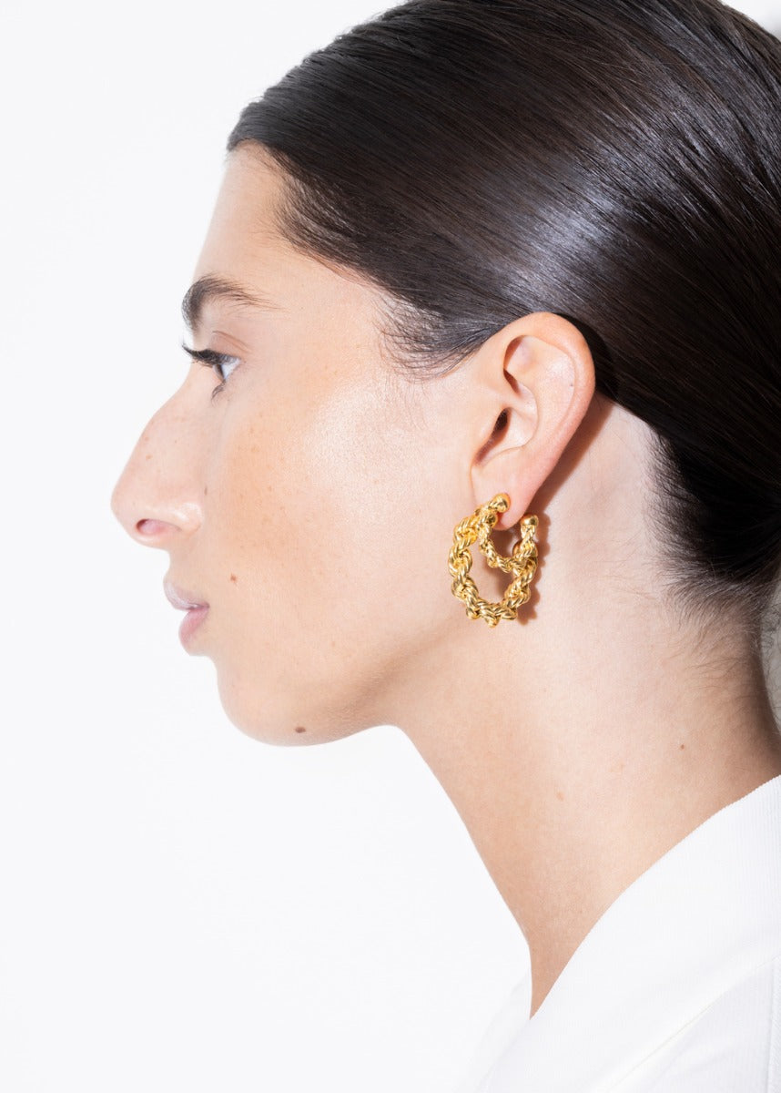 model wearing mini bia earrings and bia earrings in gold