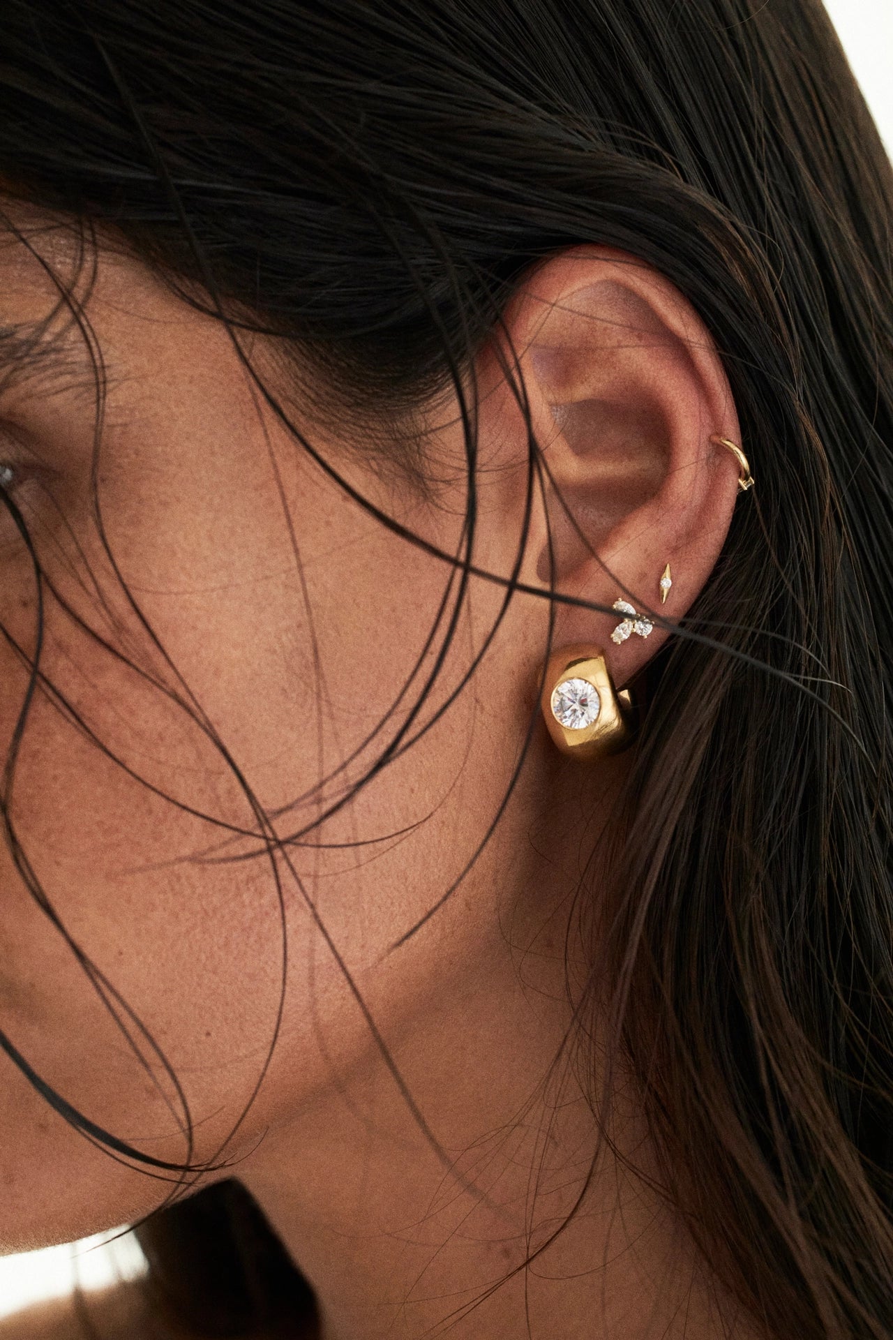 Close-up of an ear with gold earrings and a blurred background