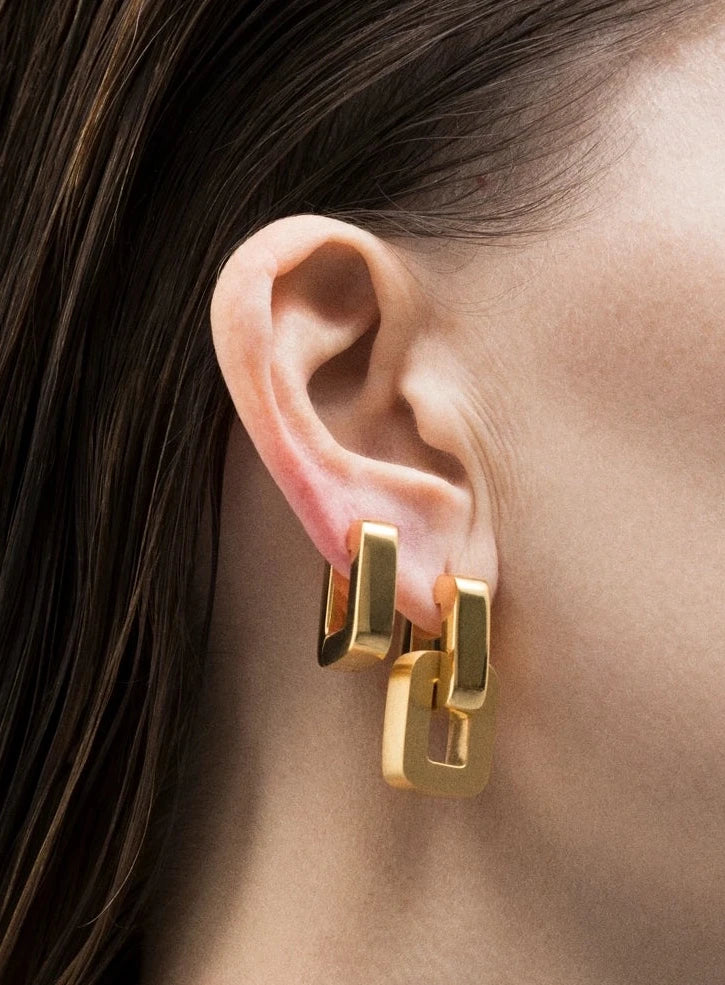 Gold earrings worn by a person with a neutral background wear in two ways