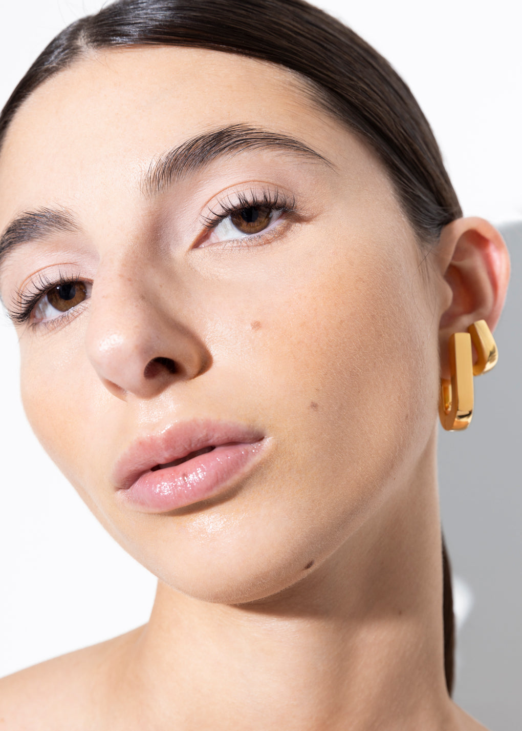 model wearing fiona earrings and fiona huggies in gold