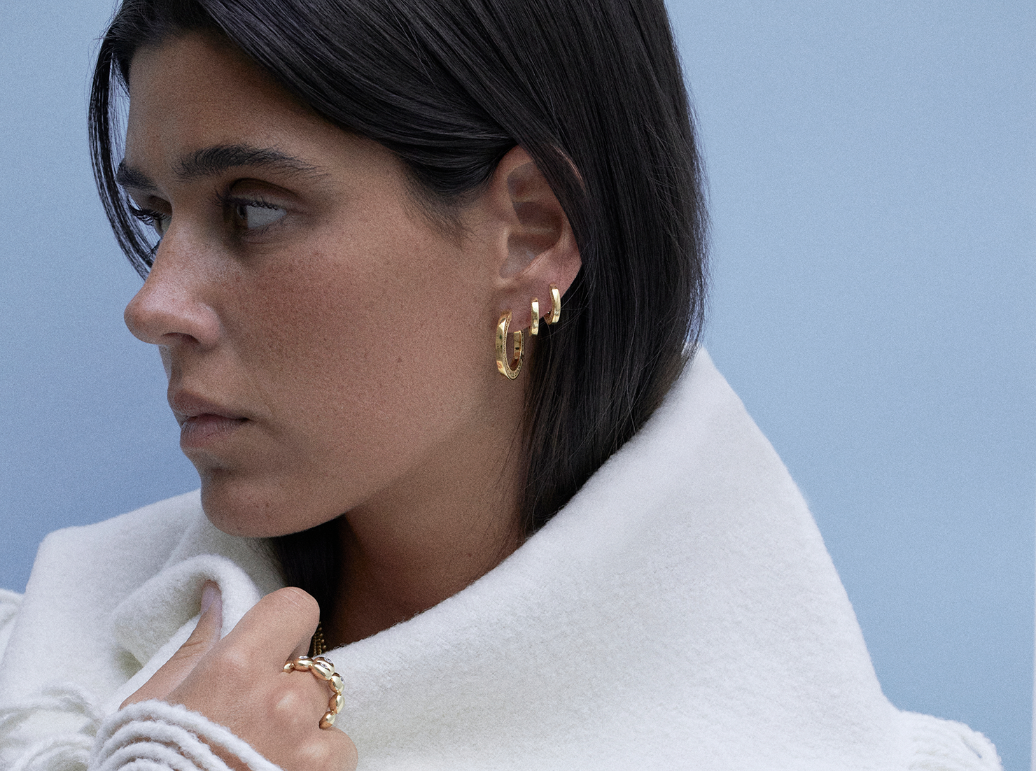 model wearing engravable hoops earrings and 18k ring with diamonds