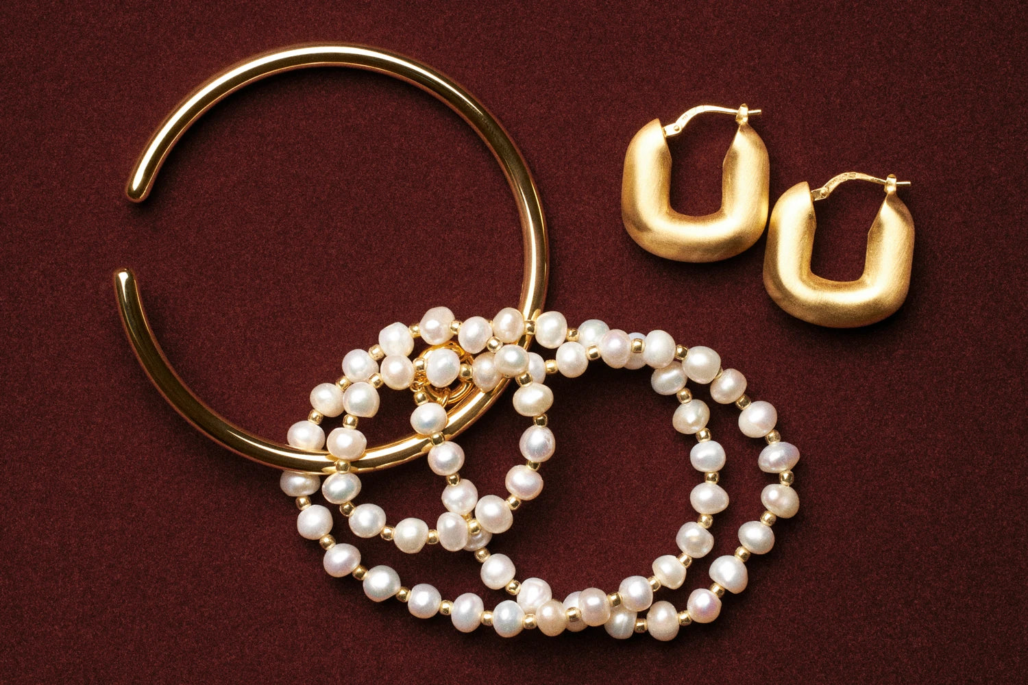 Gold and pearl jewelry on a red background