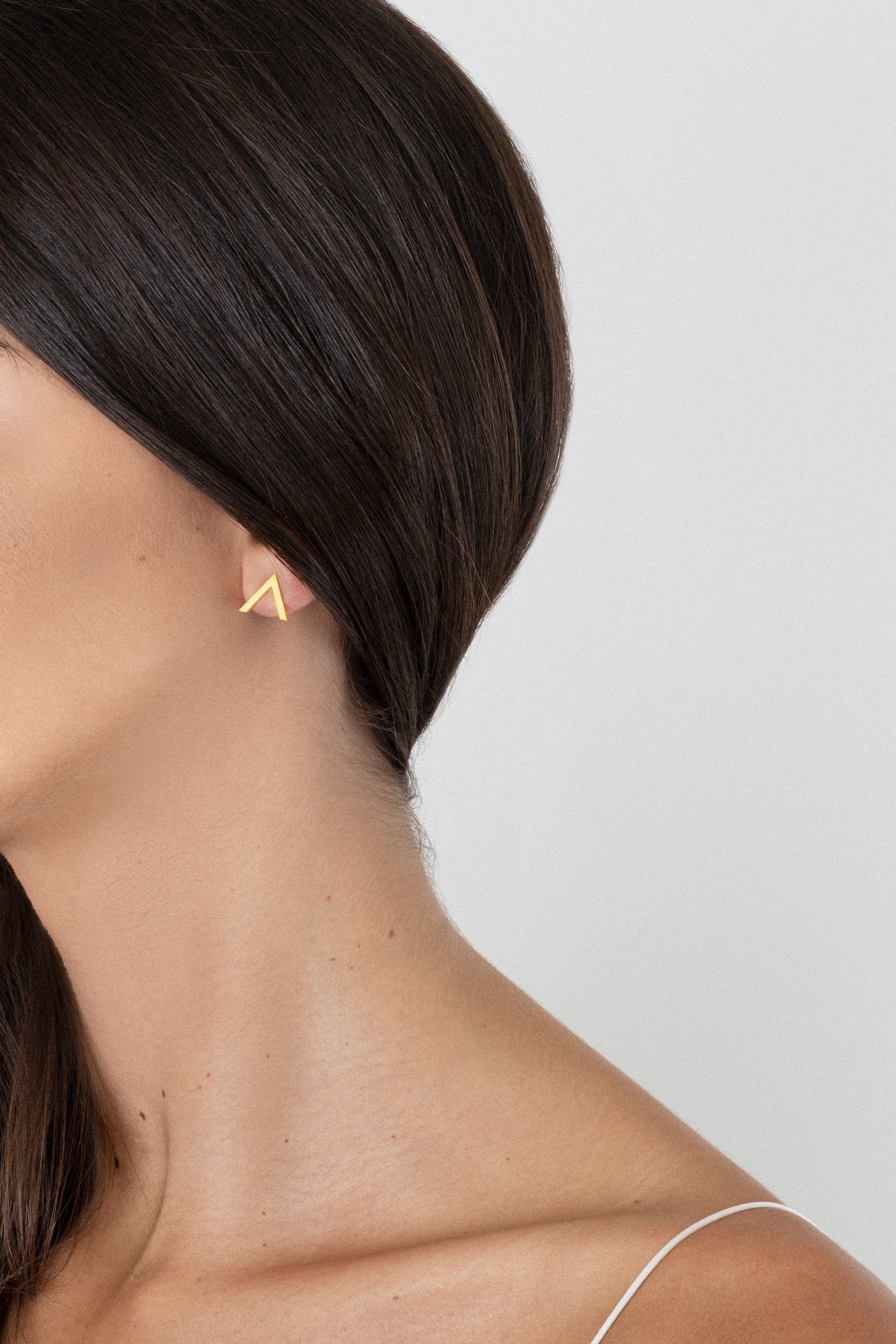 model wearing v earrings in gold